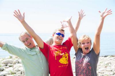 A student and his parents waving their hands next to Lake Michigan.